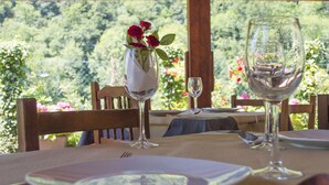 Mesa lista para comer, con un jarrón de flores y copas de vino, con vistas a un jardín exuberante.