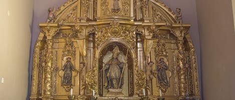 Un iconostasio religioso ricamente ornamentado, con una figura central, flanqueado por estatuas y elaborados relieves.