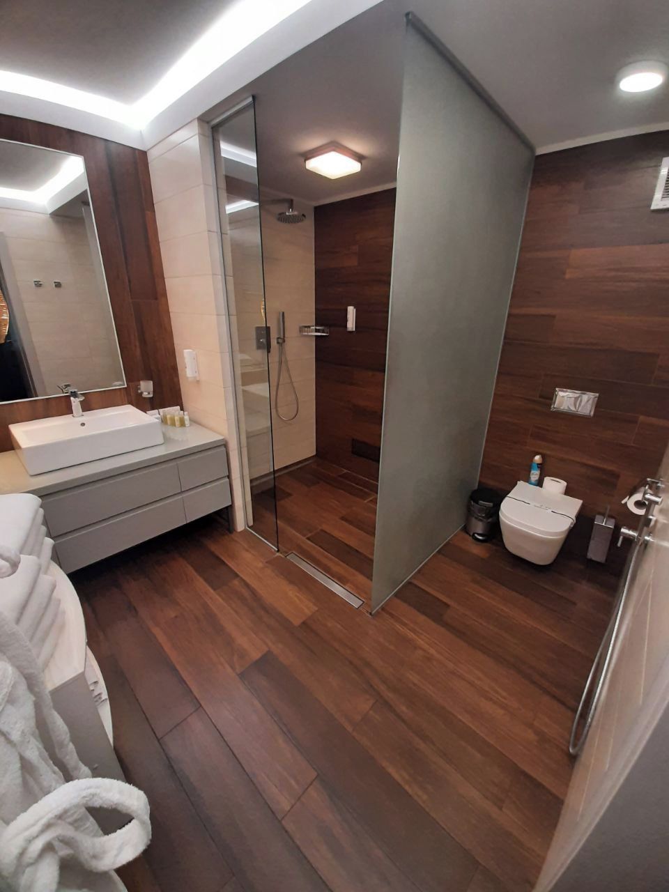 A modern bathroom with a glass shower enclosure, a sink with a mirror, and a toilet.