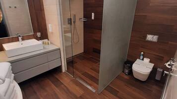 A modern bathroom with a glass shower enclosure, a sink with a mirror, and a toilet.