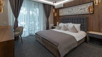 Una habitación de hotel moderna con una cama grande, un escritorio, una silla y vistas al exterior.