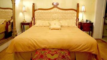 A large bed with a wooden headboard, two bedside tables with lamps, and a mirror on the wall.