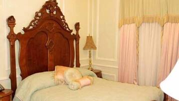 Una cama clásica con dosel y tablero de madera, una araña de cristal y colcha con estampado floral.