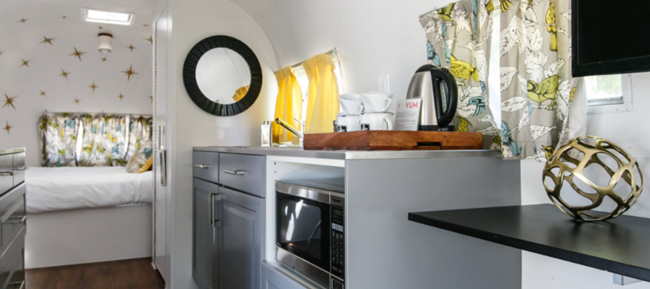 Una cocina compacta con microondas, cafetera y un cuenco decorativo en la encimera.
