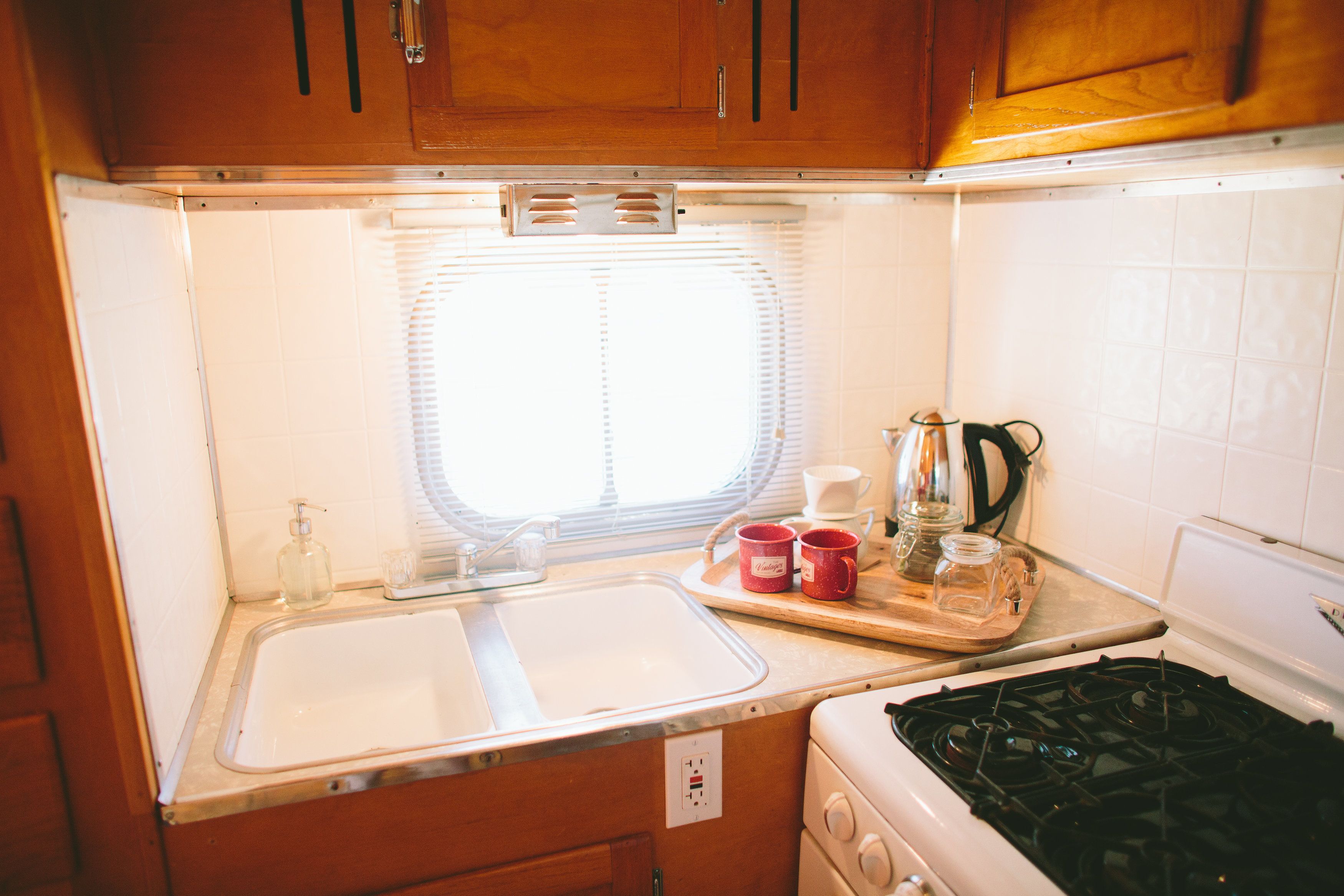 A compact kitchen with a sink, stove, and window.