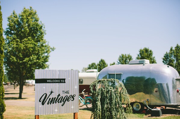 A vintage trailer with a sign reading "WELCOME TO THE VINTAGES" in a park-like setting. - The Vintages Trailer Resort (Dayton)