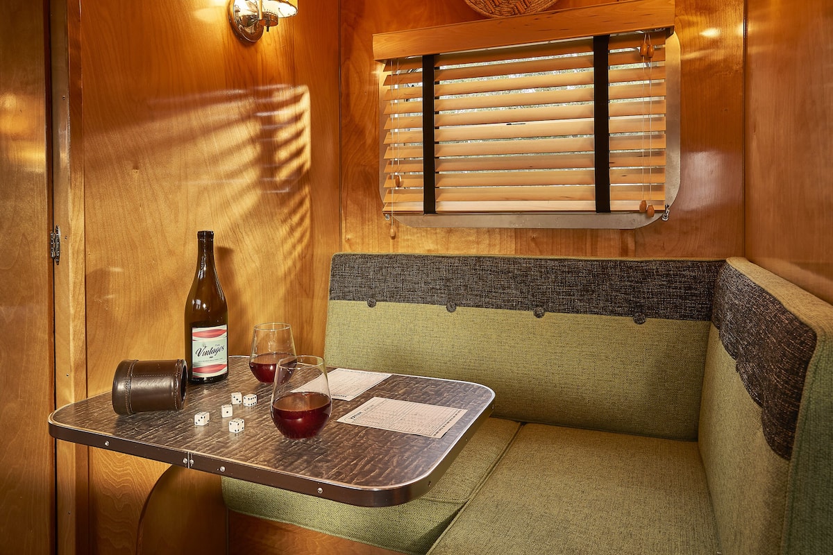 A cozy interior with a wooden table, a bottle of wine, glasses, and dice.