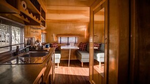 A compact kitchen with a sink, countertop, and window blinds. - The Vintages Trailer Resort (Dayton)