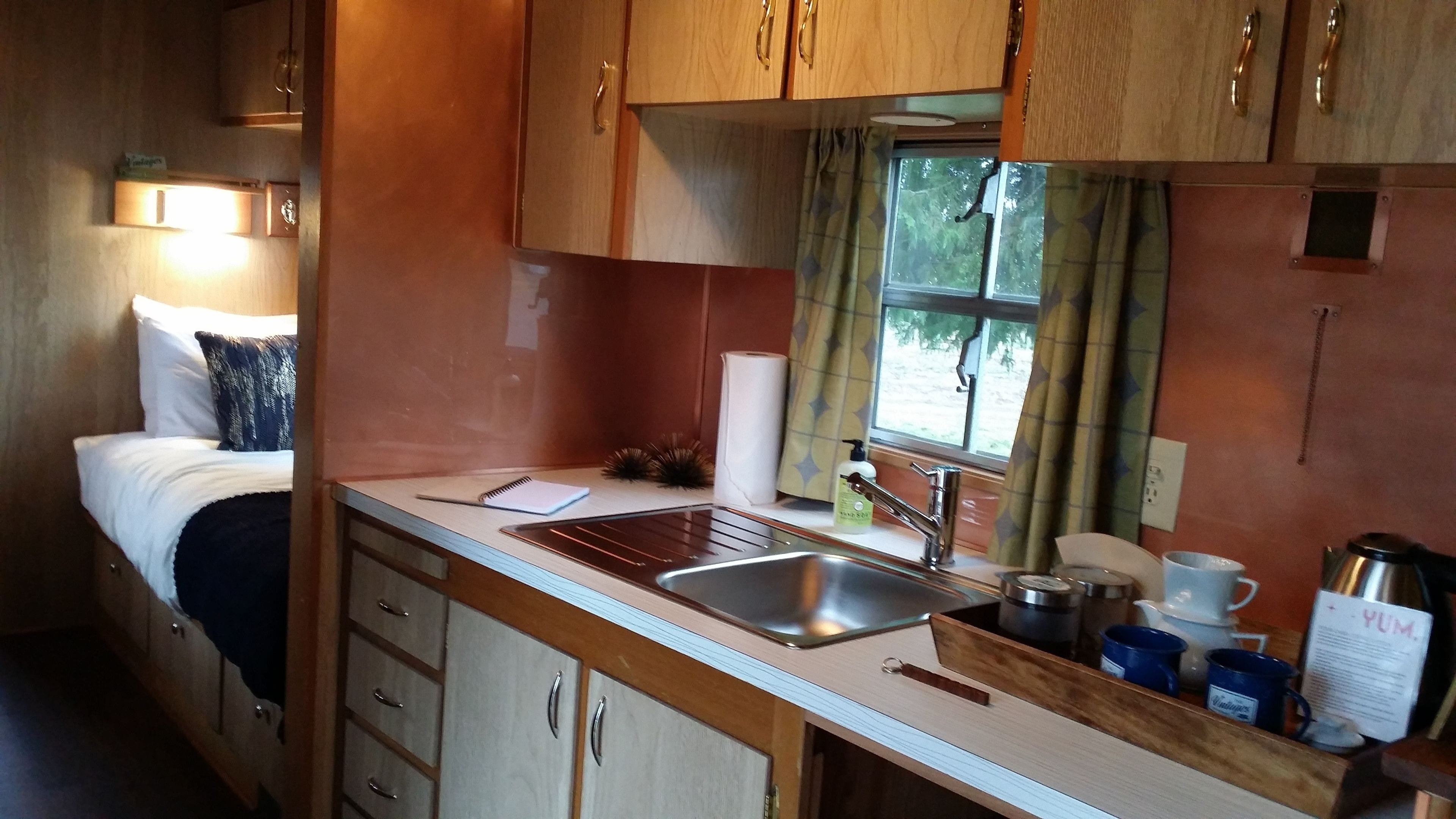 A compact kitchenette with a sink, a small countertop, and wooden cabinets.