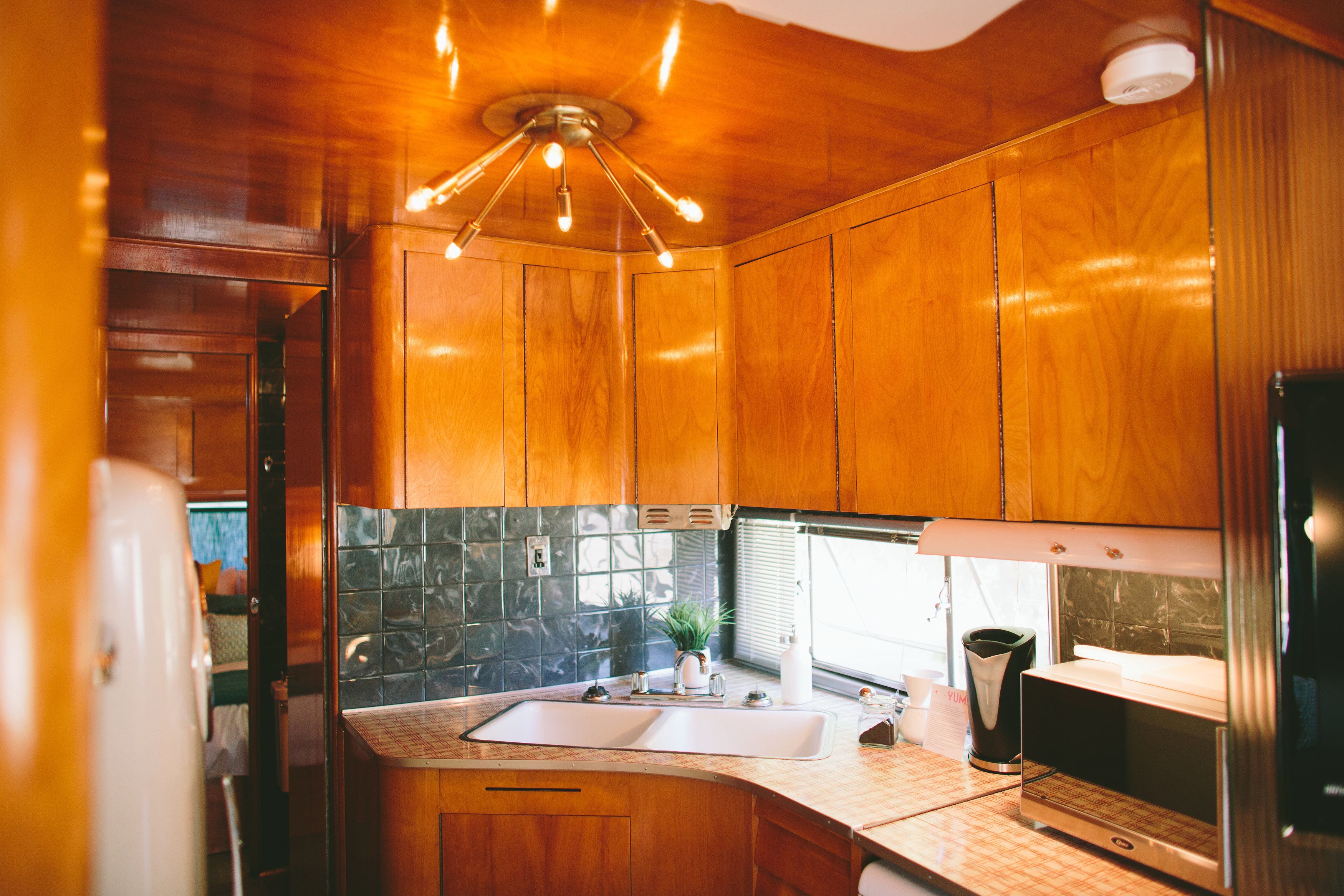 A modern kitchen with wooden cabinets, a stainless steel refrigerator, and a built-in oven.