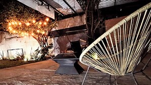 An outdoor seating area with a chair, a concrete floor, and a wall with a metal structure. - Hotel Ix by San Clemente Business Class (Tlaxcala)