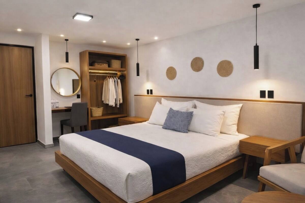 A modern bedroom with a large bed, a wooden wardrobe, a desk, and a round mirror.