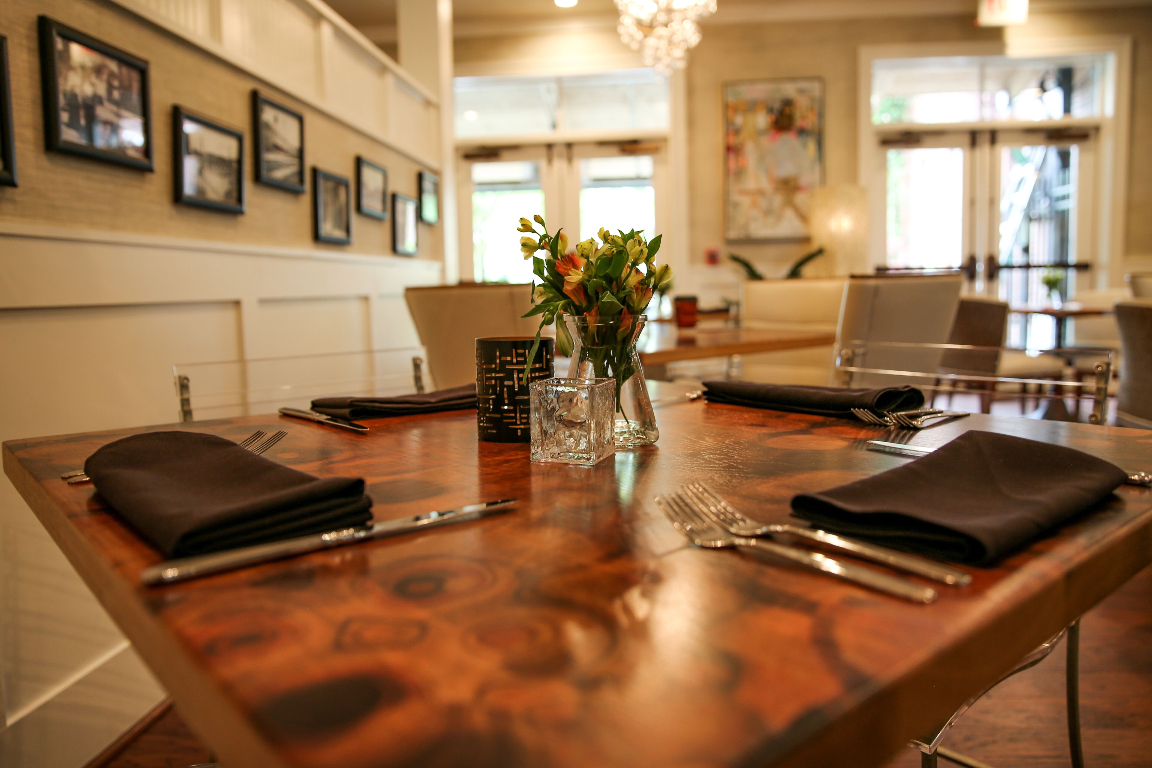 Une table à manger dressée avec un vase de fleurs, une serviette noire et des couverts.