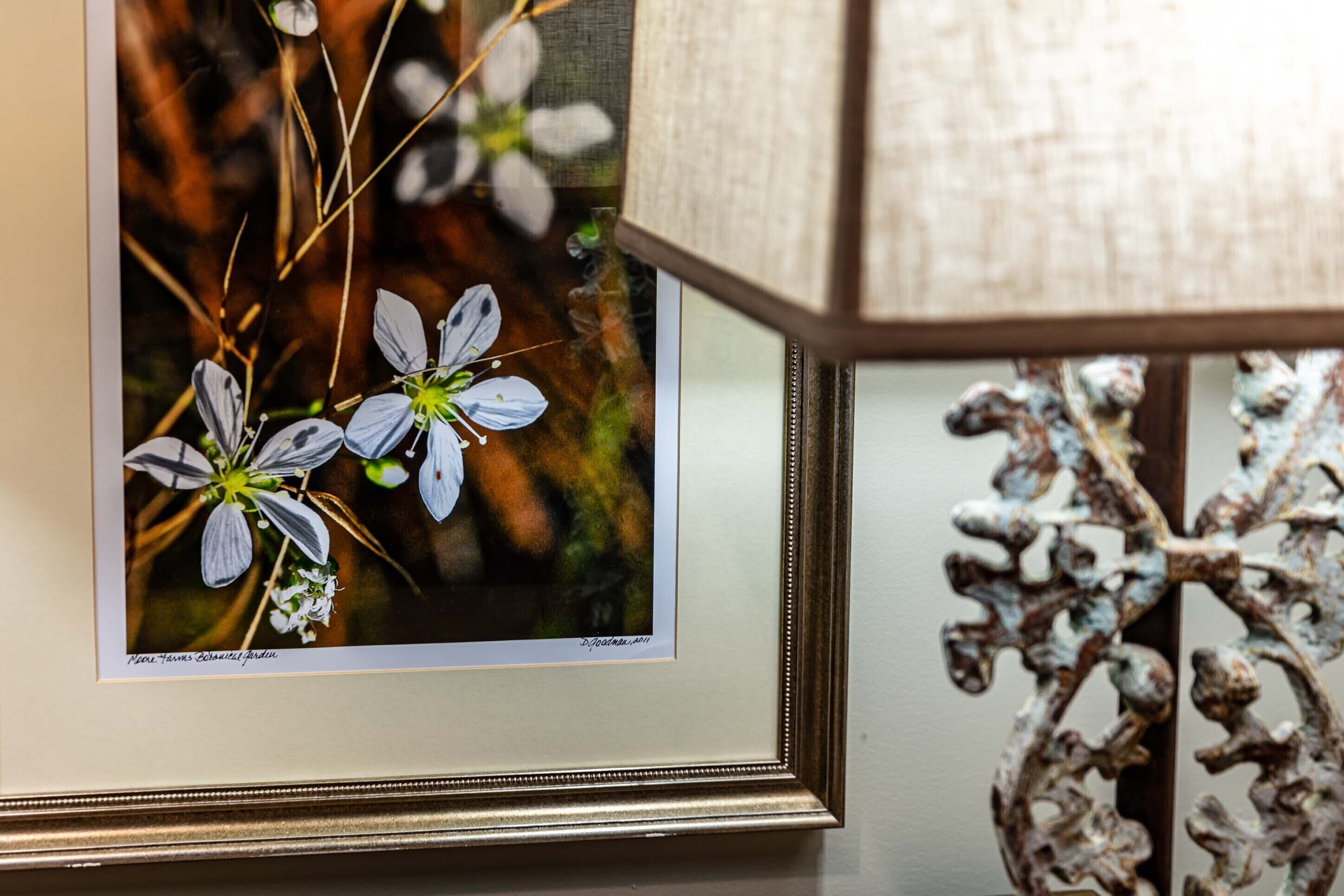 A framed photograph of flowers on a wall.