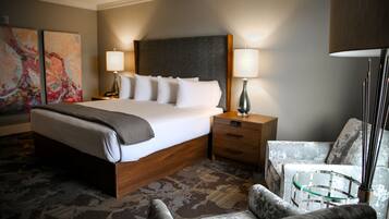 A hotel room with a large bed, two bedside tables, a chair, and a lamp.