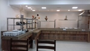 A modern kitchen with a marble countertop, wooden chairs, and a stainless steel sink.