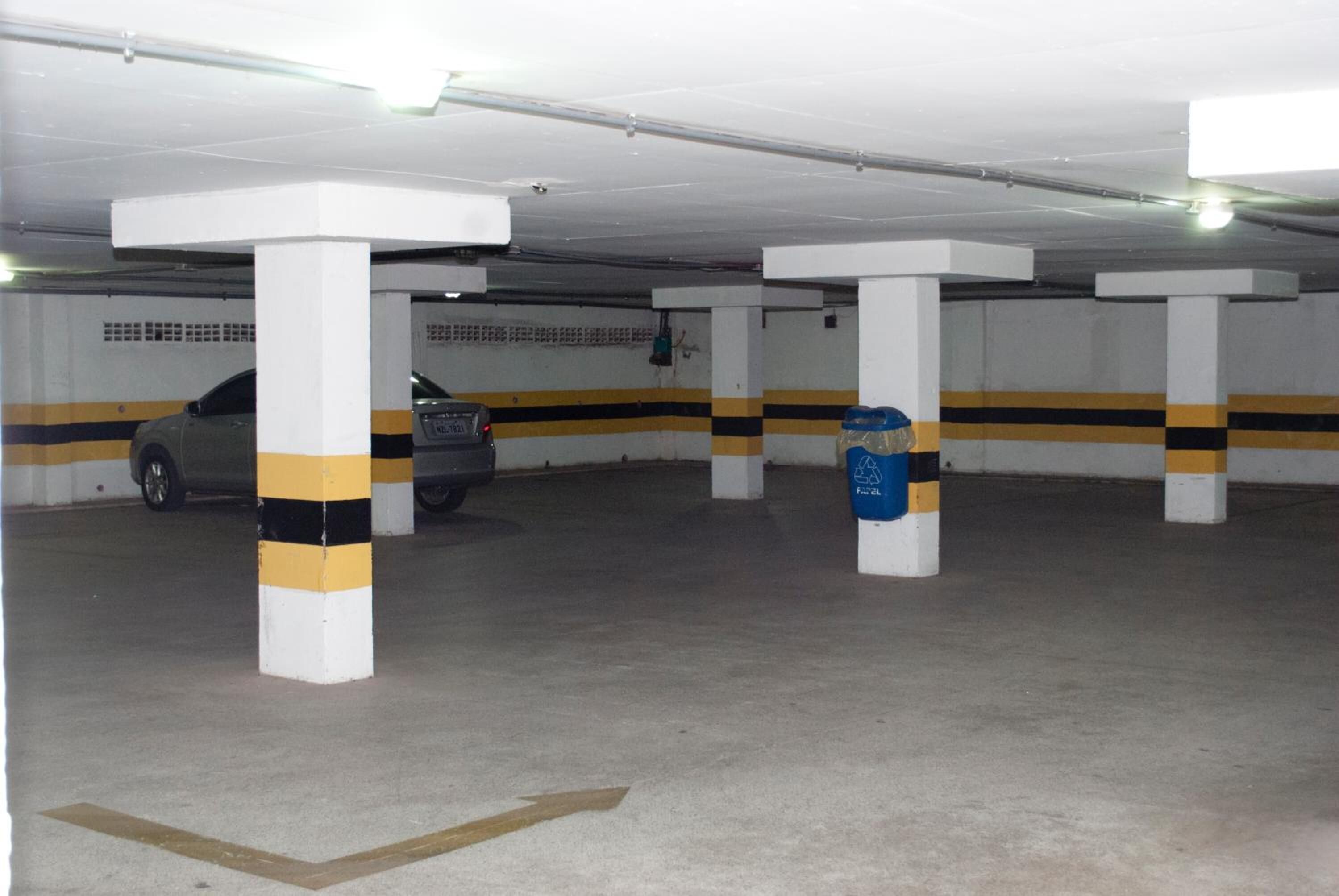Un parking avec des piliers blancs et des bandes jaunes sur les murs.