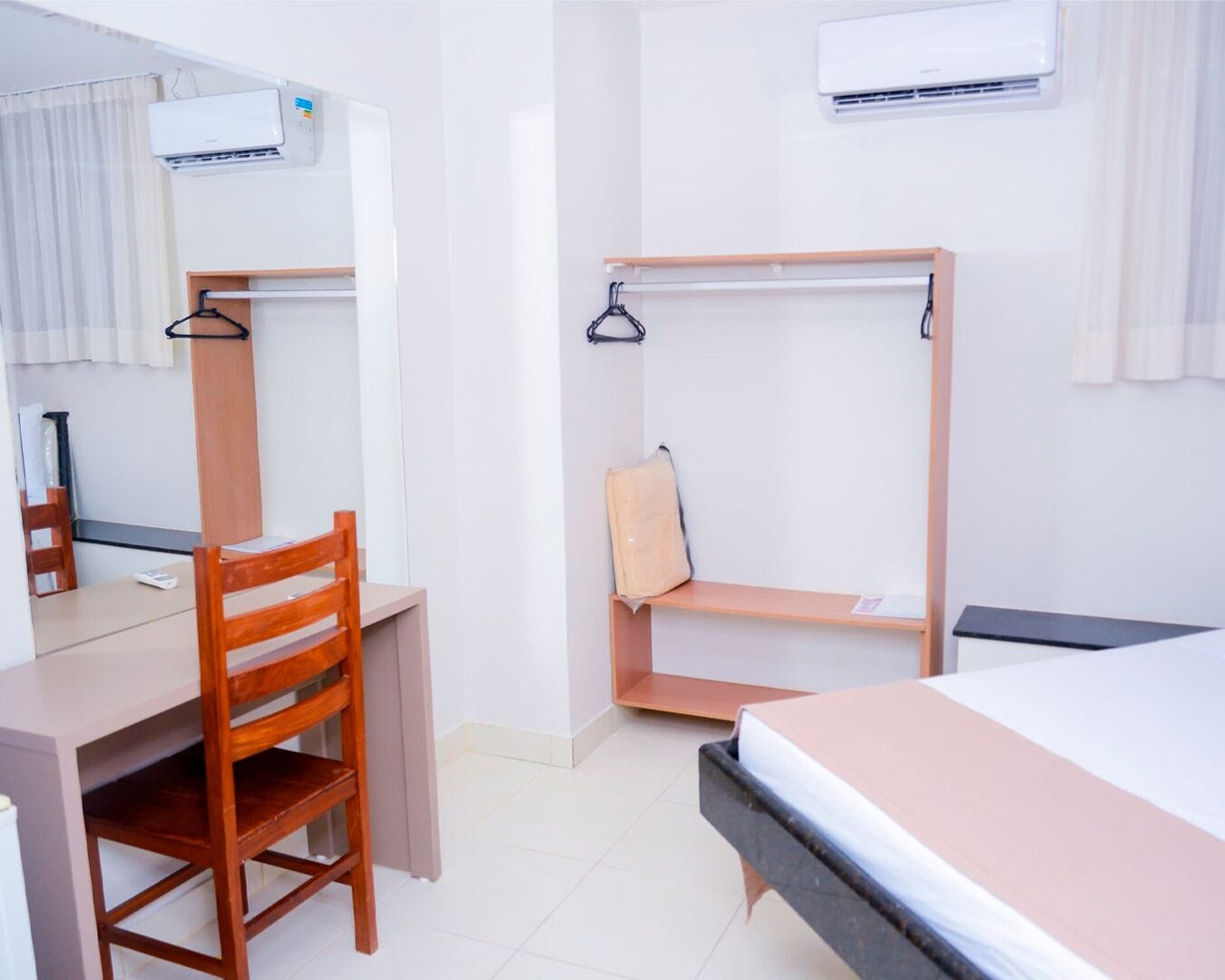 Habitación de hotel con escritorio, silla, literas y dos unidades de aire acondicionado.