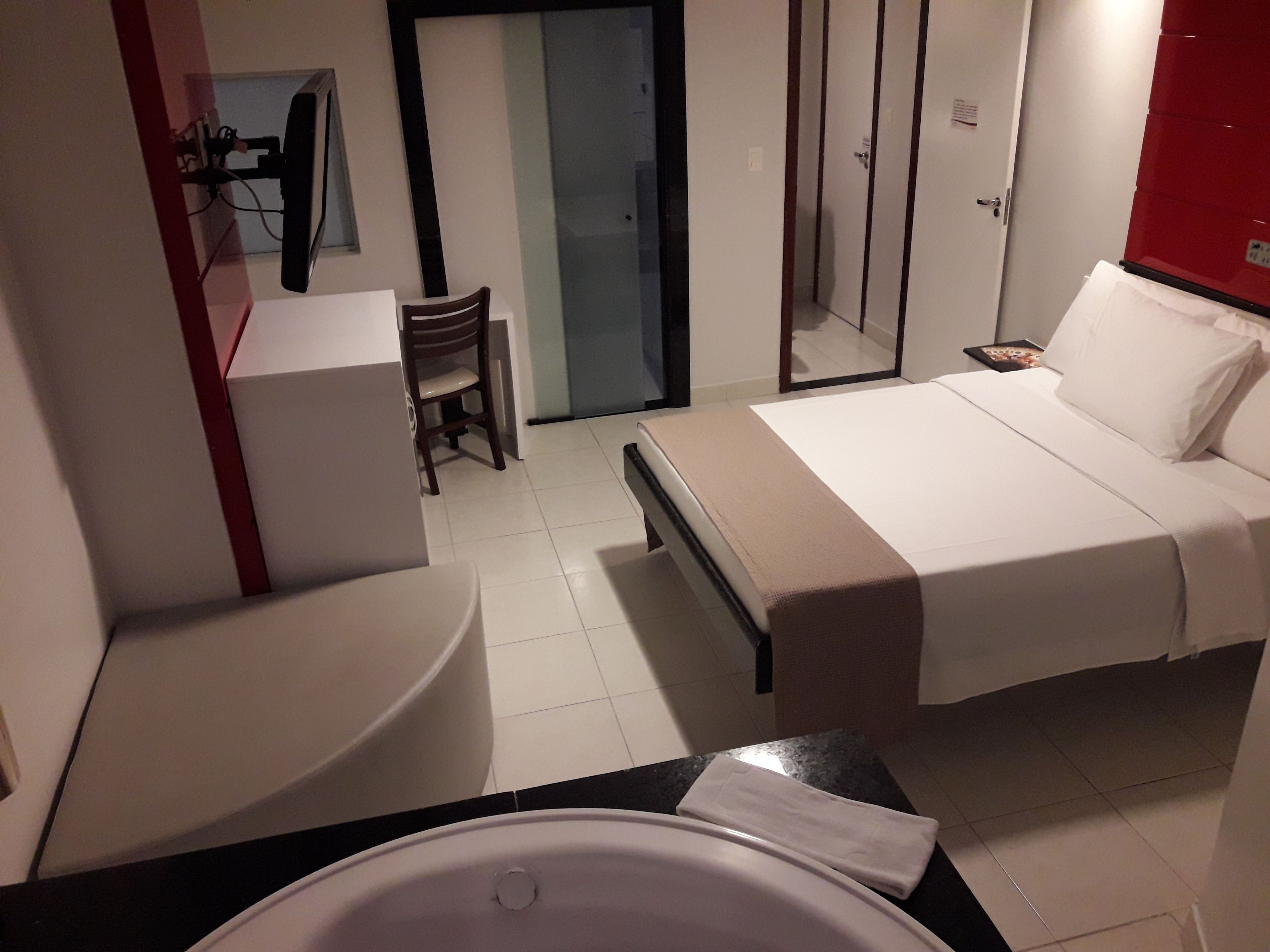 A hotel room with a bed, a desk, a chair, and a bathroom.