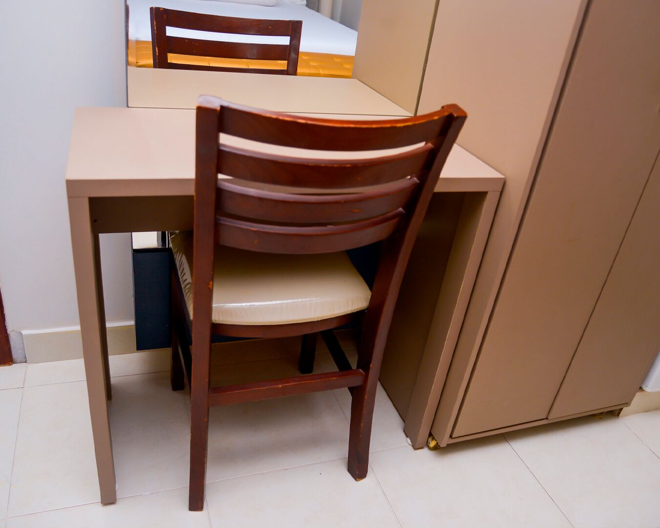 A wooden chair with a cushioned seat and backrest, positioned at a table with a white surface.