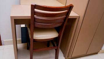 A wooden chair with a cushioned seat and backrest, positioned at a table with a white surface.