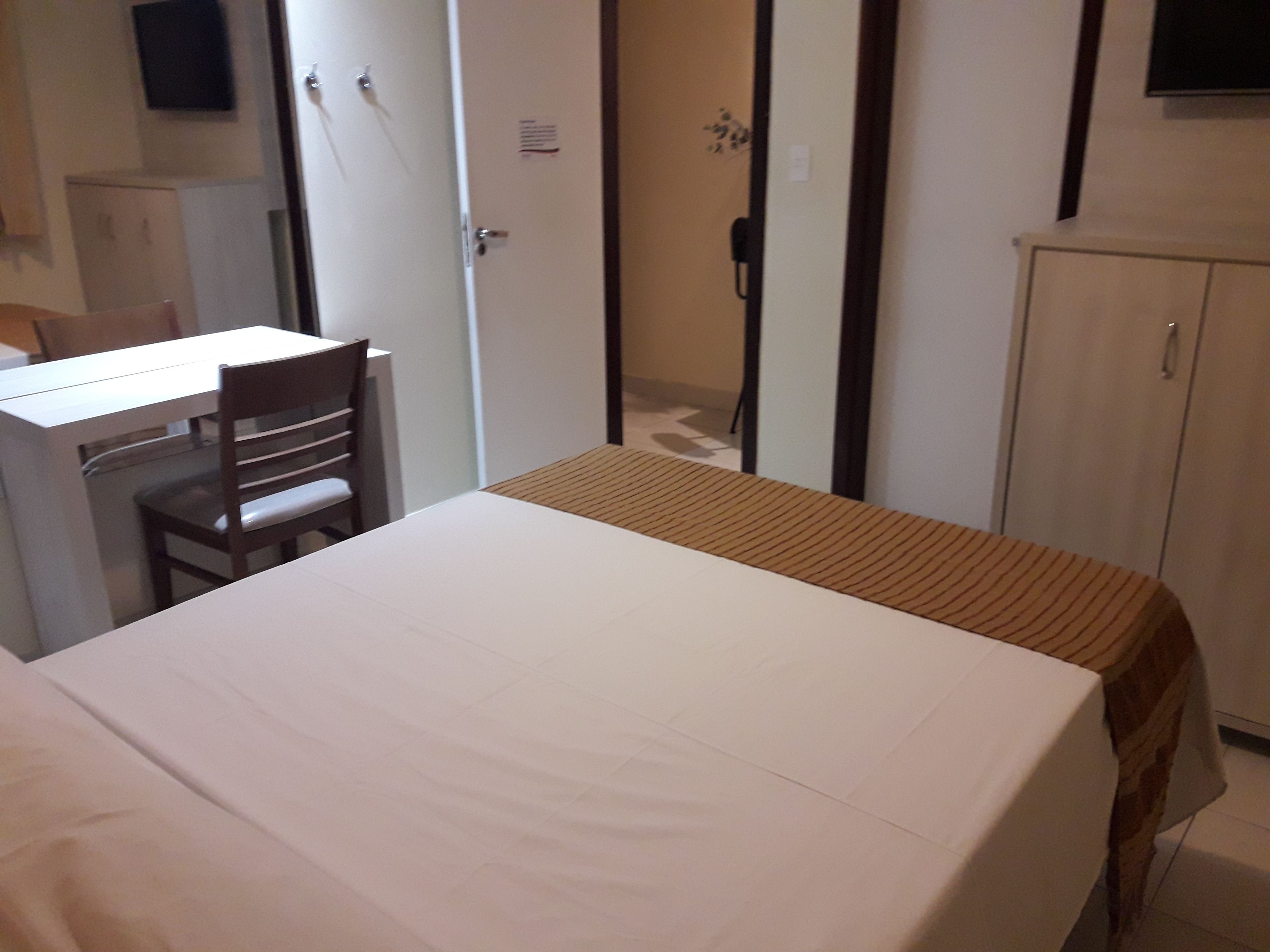 A hotel room with a bed, a desk, and a wardrobe.