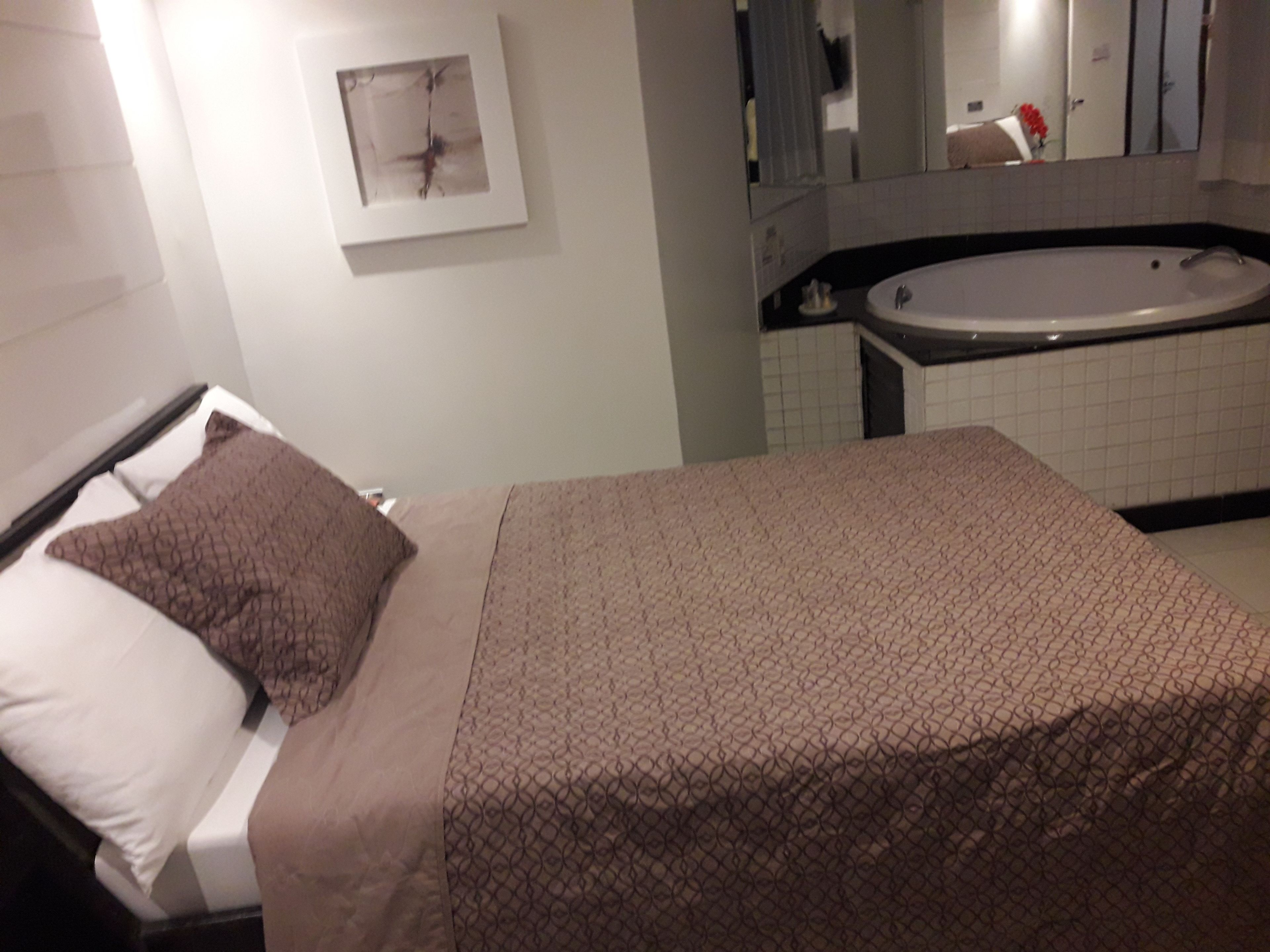 Un dormitorio con cama, un ventanal amplio y un baño con bañera.