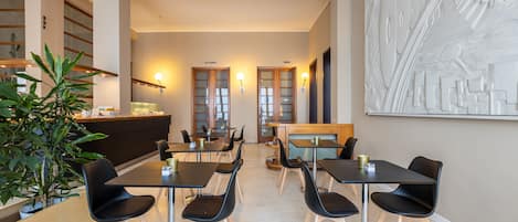 Un comedor moderno con mesas y sillas, una recepción y una gran obra de arte abstracta en la pared.