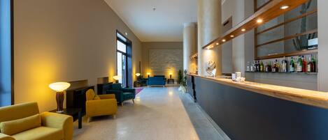 A modern lobby with a reception desk, seating area, and a bar.