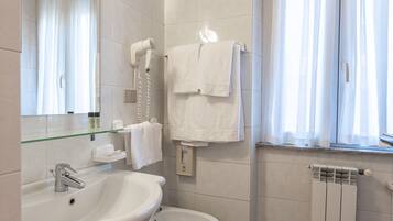 A modern bathroom with a sink, bidet, and a mirror.