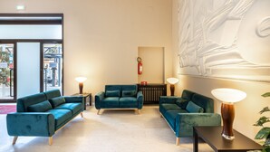 A modern lobby with teal sofas, a coffee table, and a wall-mounted lamp.