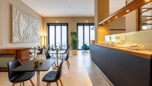 A modern dining area with tables and chairs, a reception desk, and a buffet counter.