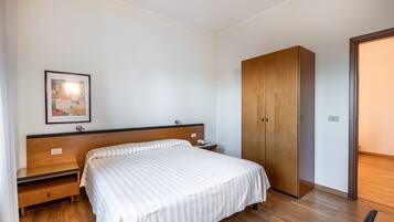 A bedroom with a bed, wooden wardrobe, nightstand, and a framed picture on the wall.