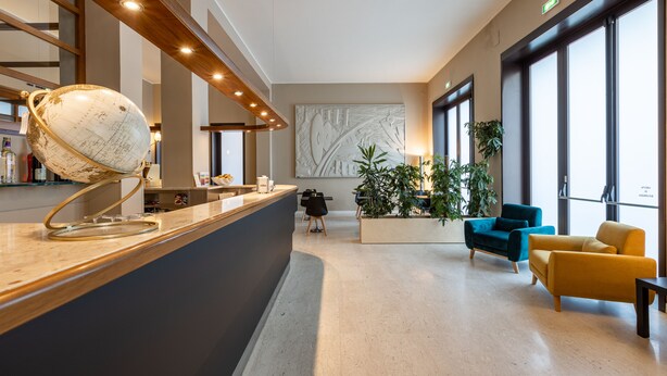 A modern lobby with a reception desk, a globe, seating area, and large windows.