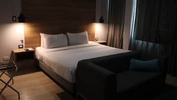 Un dormitorio moderno con una cama grande, mesitas de noche, un sofá y una lámpara colgante.