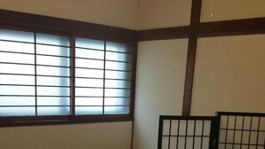 A traditional Japanese room with tatami flooring, a shoji screen, and a low wooden table. - Tenma Itoya Guest House - Hostel (Osaka)