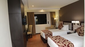 Een hotelkamer met twee bedden, een bureau, een stoel en een televisie.