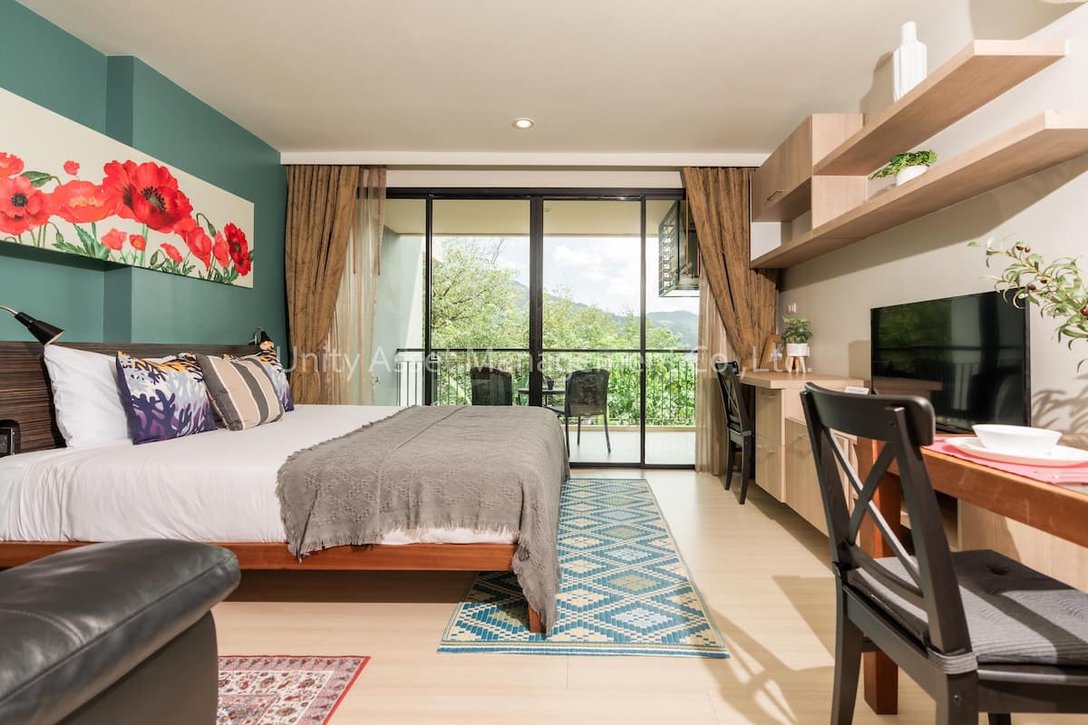 A modern bedroom with a bed, a TV, a balcony, and a dining area.