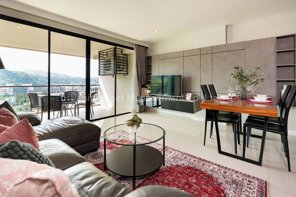A modern living room with a sofa, a glass coffee table, a dining area with a table and chairs, a TV, and a view of the city.