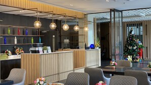 A modern hotel lobby with a reception desk, seating area, and a Christmas tree. - Brighton Hotel Bangkok (Bangkok)
