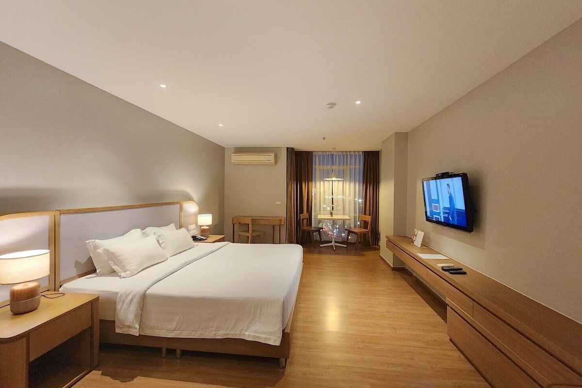 Une chambre d’hôtel équipée d’un lit, de tables de chevet, d’un bureau, d’une chaise, d’un téléviseur et d’un appareil de climatisation.