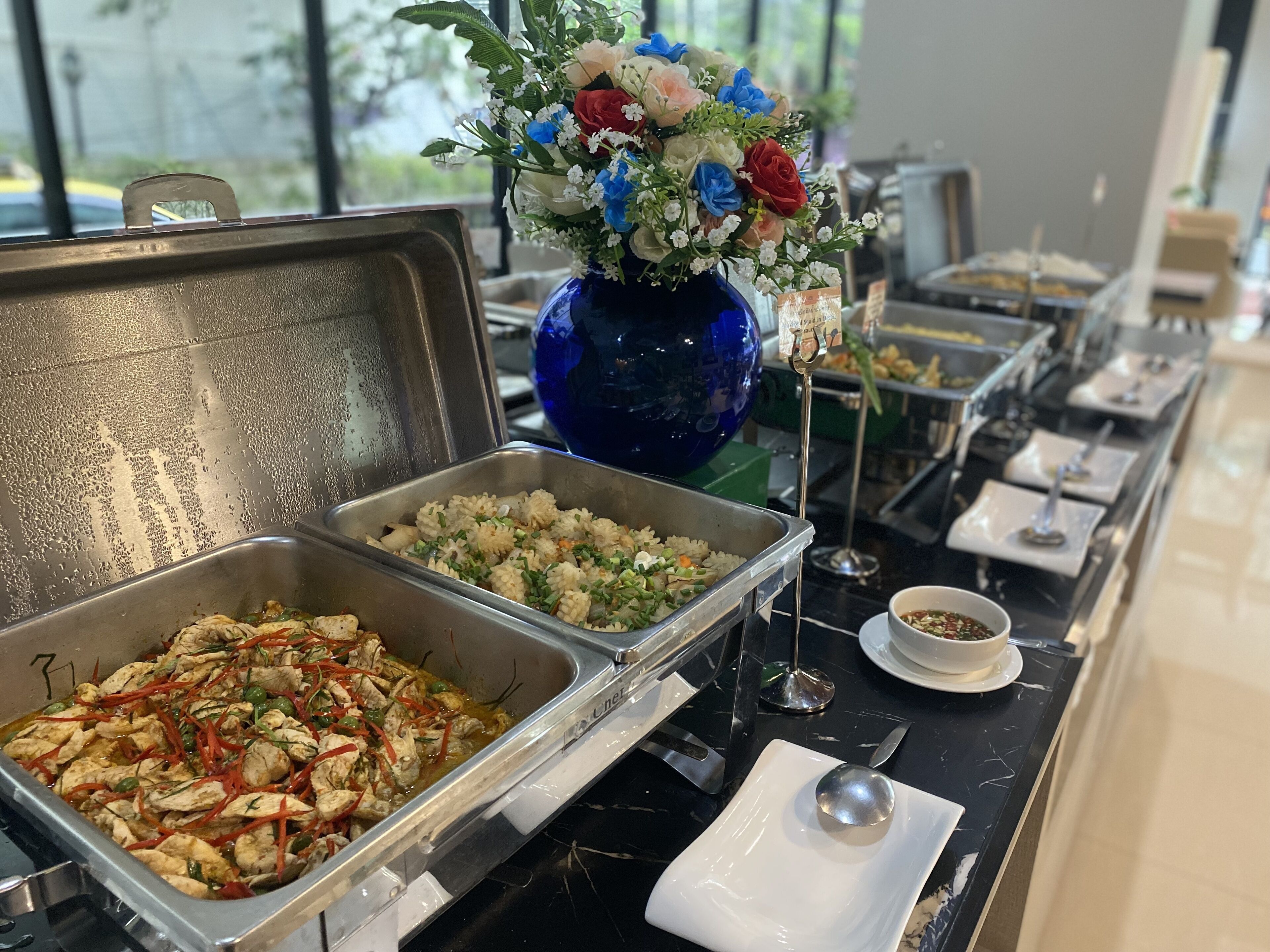 A buffet setup with various food items and a decorative vase with flowers.