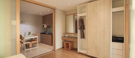 A modern bedroom with a wooden floor, a bed, a wardrobe, and a bathroom visible through an open door.