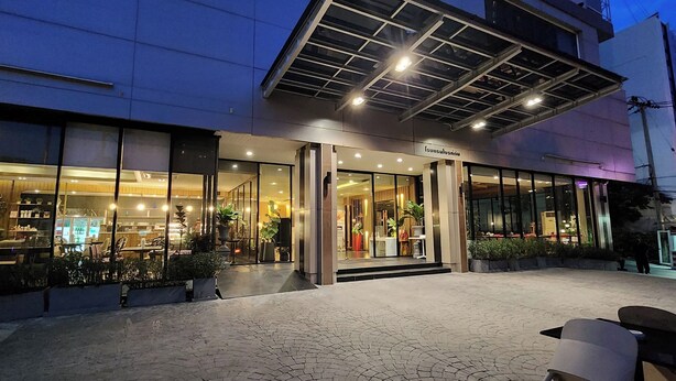A modern hotel entrance with glass doors, potted plants, and a paved outdoor area. - Brighton Hotel Bangkok (Bangkok)