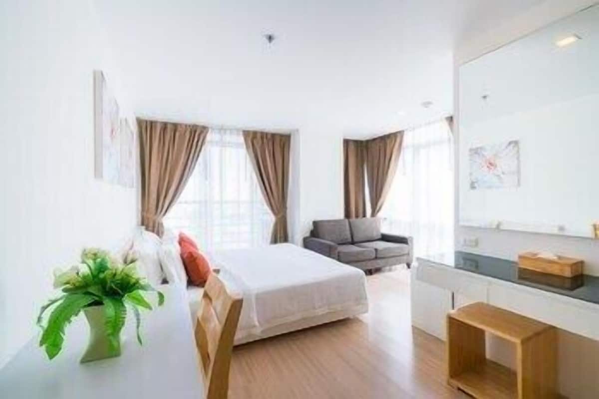 Une chambre d’hôtel moderne, équipée d’un lit, d’un canapé, d’une petite table et d’un miroir.