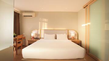 A hotel room with a large bed, bedside tables with lamps, a desk, and a chair.