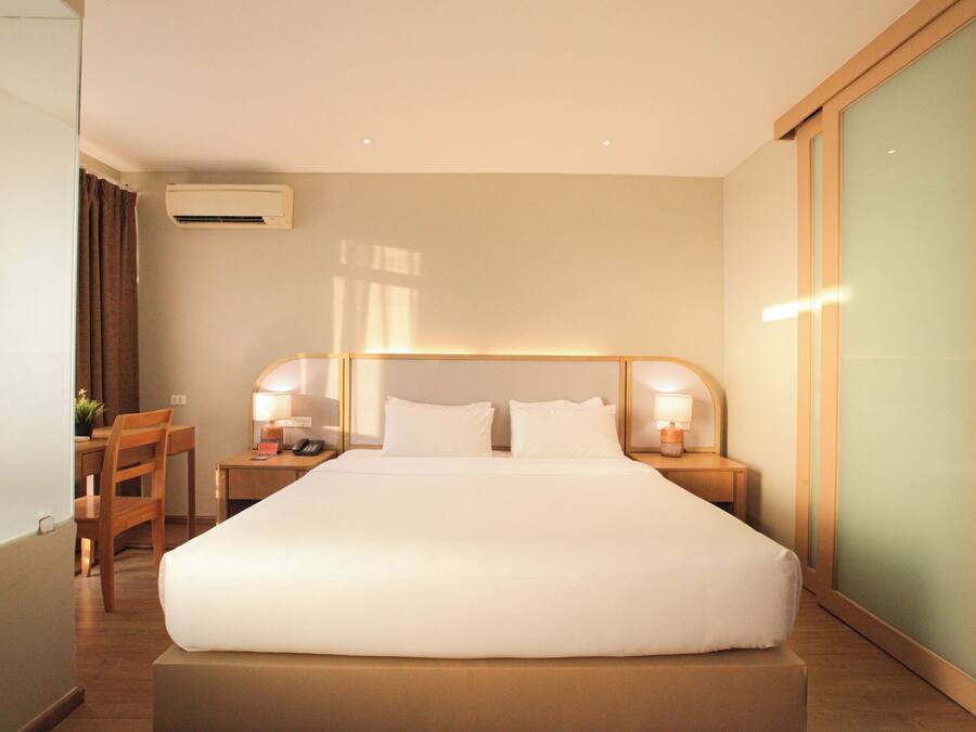 A hotel room with a large bed, bedside tables with lamps, a desk, and a chair.