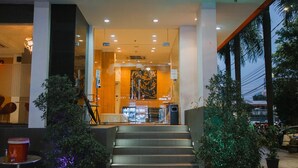 Entrada de hotel con una escalera que conduce al vestíbulo, destacando un diseño moderno con puertas de vidrio y un ventanal grande.