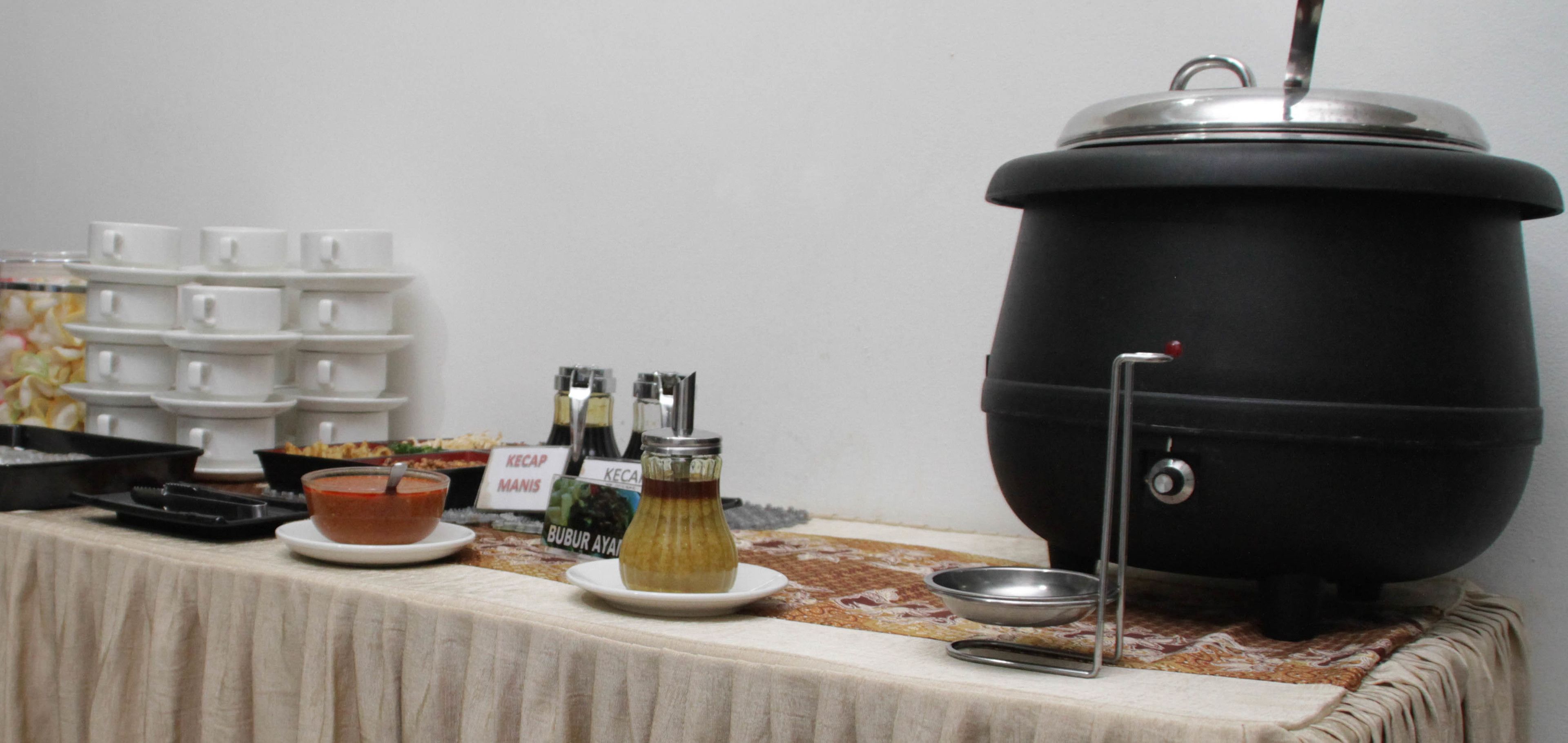 A buffet table with a large pot, serving dishes, and condiments.