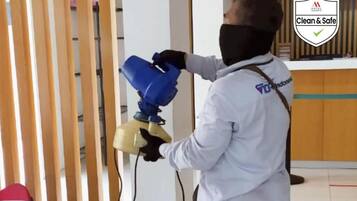 A person in a white uniform spraying a cleaning solution on a wooden partition.